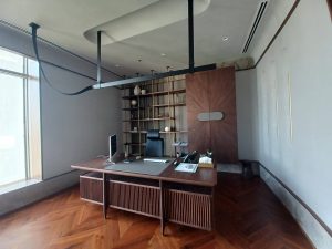 Features a bespoke wooden desk and a stunning sunburst-veneer storage unit that serves as a commanding focal point.